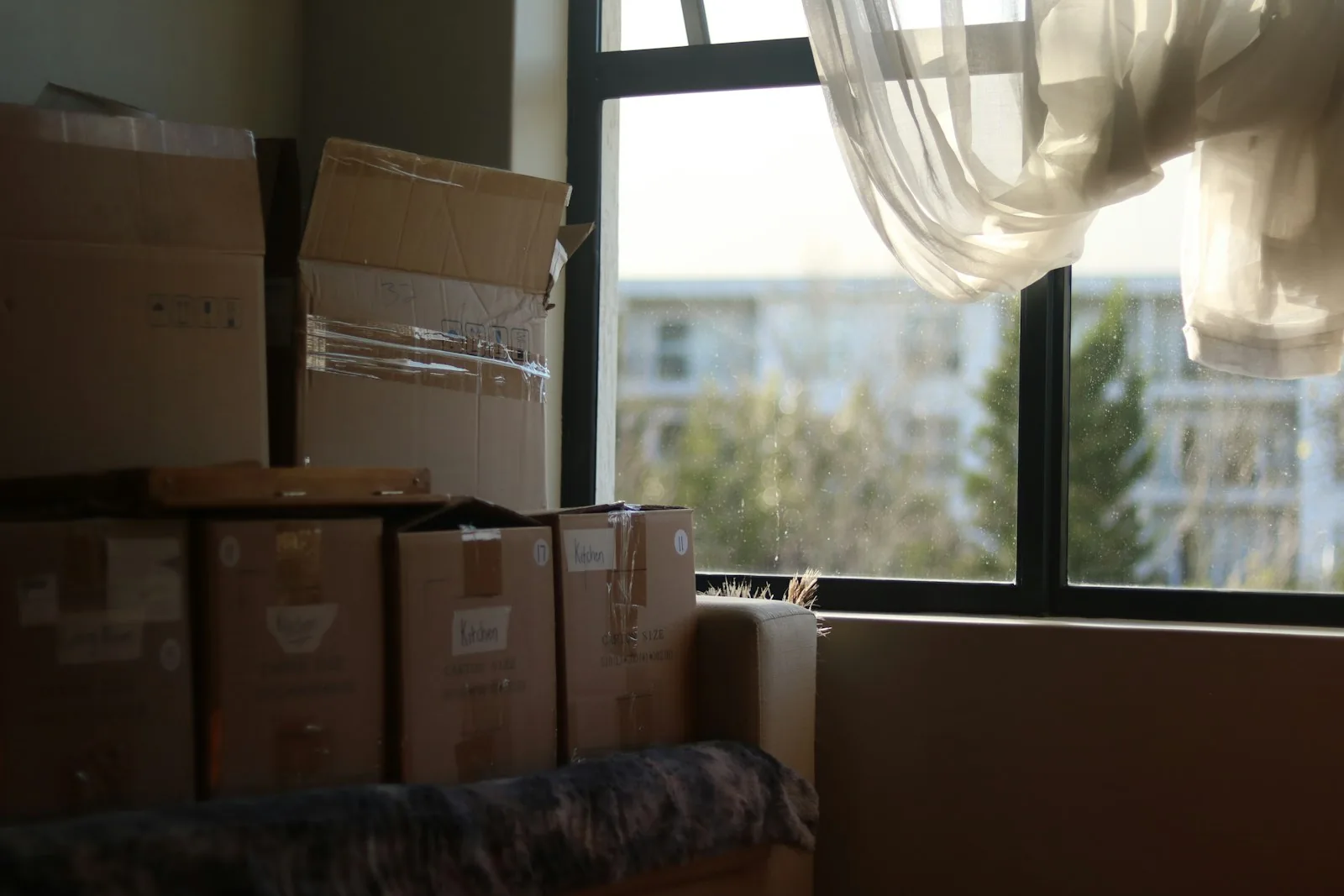 Cartons de déménagement empilés près d'une fenêtre lumineuse